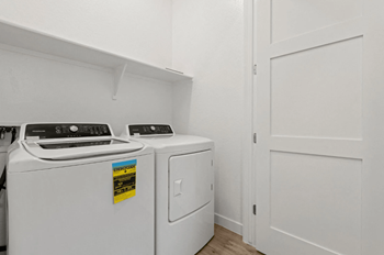 Two white front loading washing machines in a laundry room.
